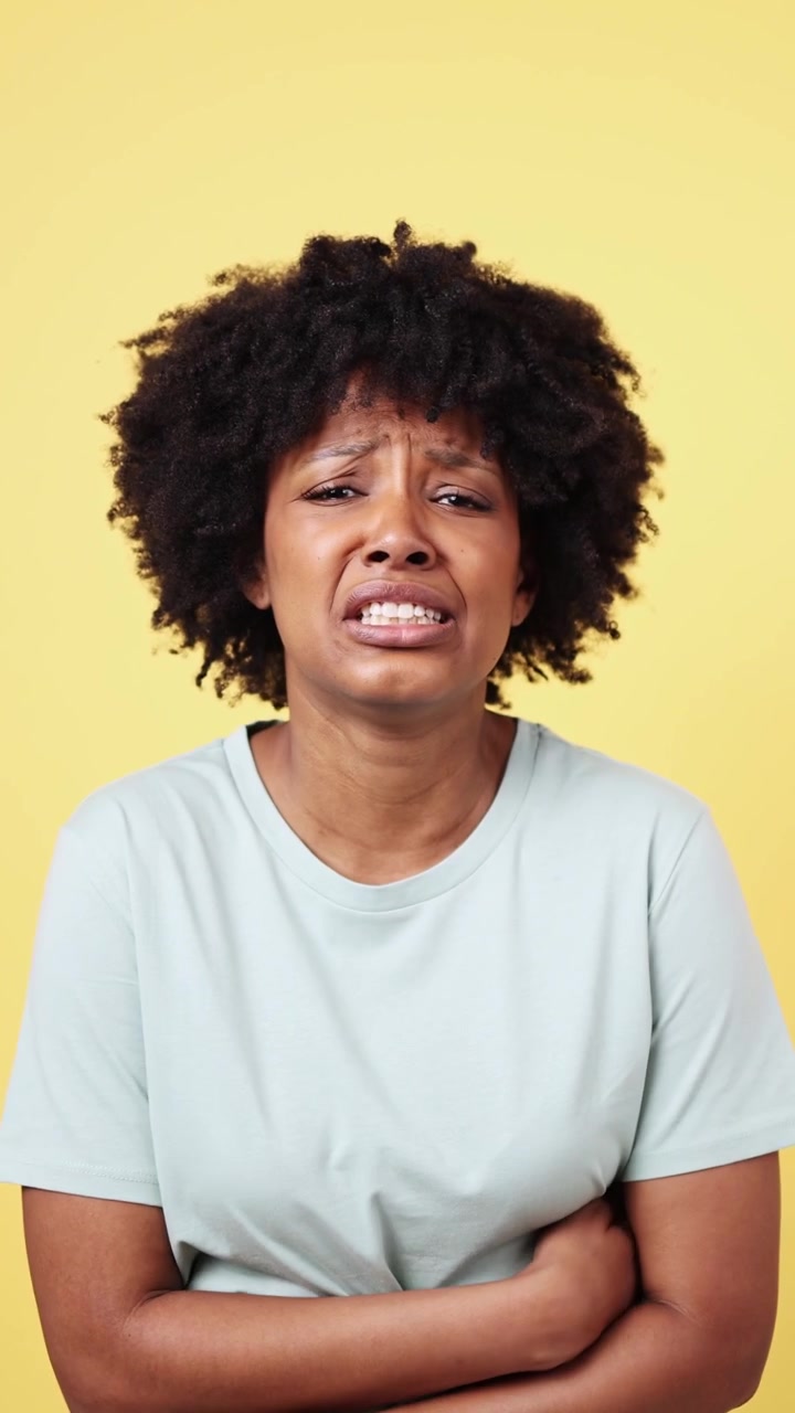 Donna africana che prova dolore allo stomaco su sfondo giallo