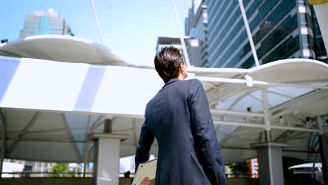 caucasian businessman holding tablet walking in the city