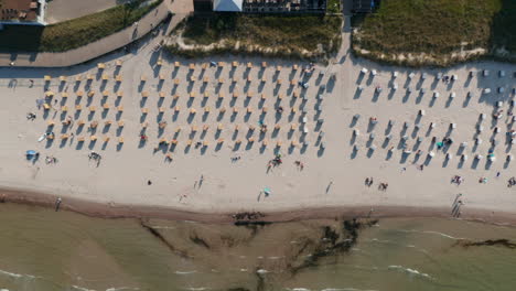 Touristischer-Strand-In-Der-Ostsee,-Gesehen-Aus-Der-Vogelperspektive-Von-Oben-Nach-Unten,-Drohnenansicht,-Strand-Mit-Stühlen-Und-Touristen,-Die-Die-Sommersonne-Genießen,-Seitwärts,-Tag