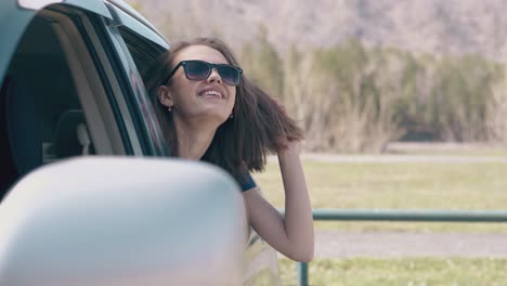 young woman looks at car side mirror by spring rural site