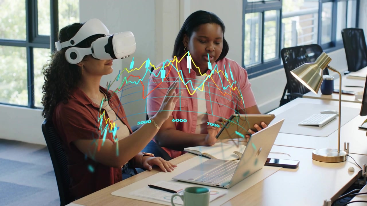 VR user moving hands, manipulating finance charts while colleague tapping tablet reviewing data