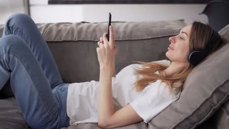 Girl-in-headphones-enjoying-the-rhythm-of-the-music,-holding-smartphone