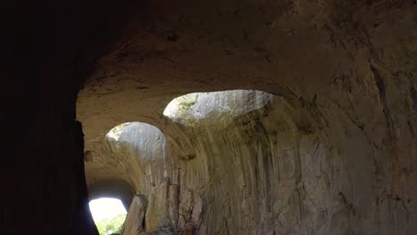 Panorámica-De-Izquierda-A-Derecha-Que-Muestra-El-Agujero-Icónico-Comúnmente-Llamado-Ojos-De-Dios-Dentro-De-La-Cueva-De-Prohodna,-Ubicada-En-Karlukovo,-Bulgaria