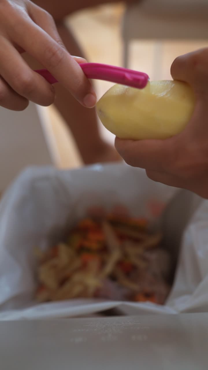 Hands peeling a potato with a pink peeler