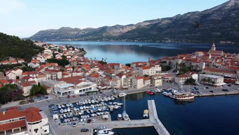 Island-of-Korcula-in-Adriatic-sea-and-mountains-in-the-background,-Croatia,-Drone-shot