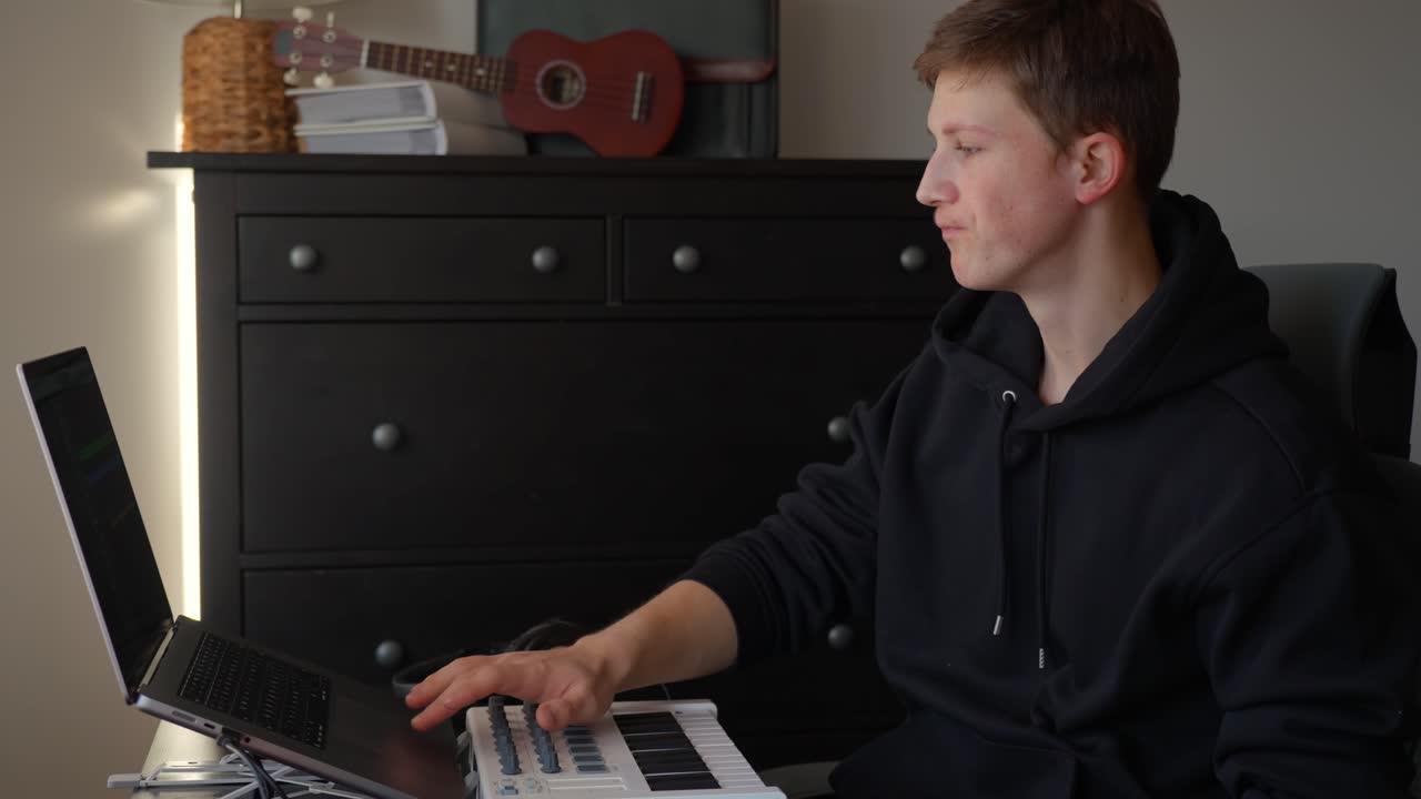Young man creates music in home studio, focused and inspired