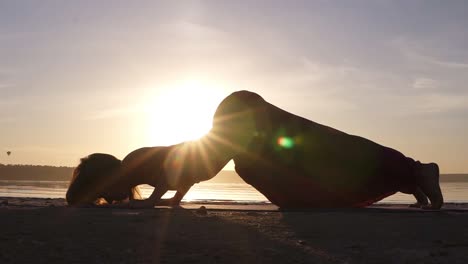 A-silhouette-footage-of-a-woman-who-is-doing-Urdhva-Mukha-Shvansana-on-the-beach.-Backbend.-Sun-shines-on-the-background