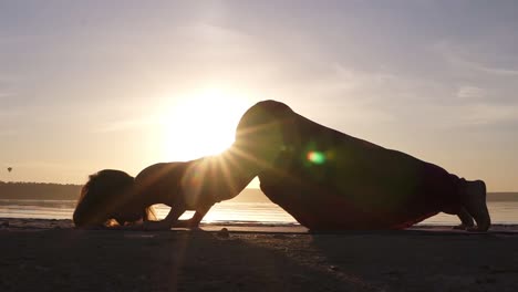 a silhouette footage of a woman who is doing urdhva mukha shvansana on the beach. backbend. sun shines on the background