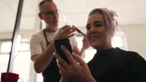 Low-angle-view-woman-using-phone-while-hair-styled