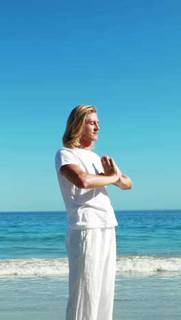 man performing yoga at beach