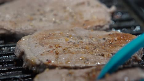 Close-up-of-turning-steaks-on-grill