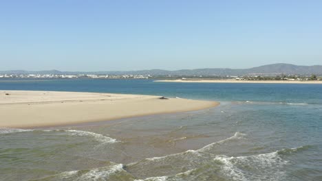 Beautiful-golden-beach-surrounded-by-perfect-blue-waters-and-bathing-in-sunlight,-Algarve-Portugal