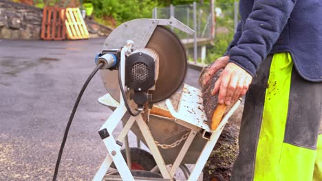 Man-using-crosscut-saw-to-cut-firewood-from-wooden-pine-planks---Closeup-of-saw-and-wood-falling-into-wheelbarrow-in-20-percent-slow-motion-and-blurred-background-1