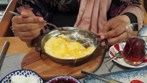 woman eating breakfast of scrambled eggs and turkish tea