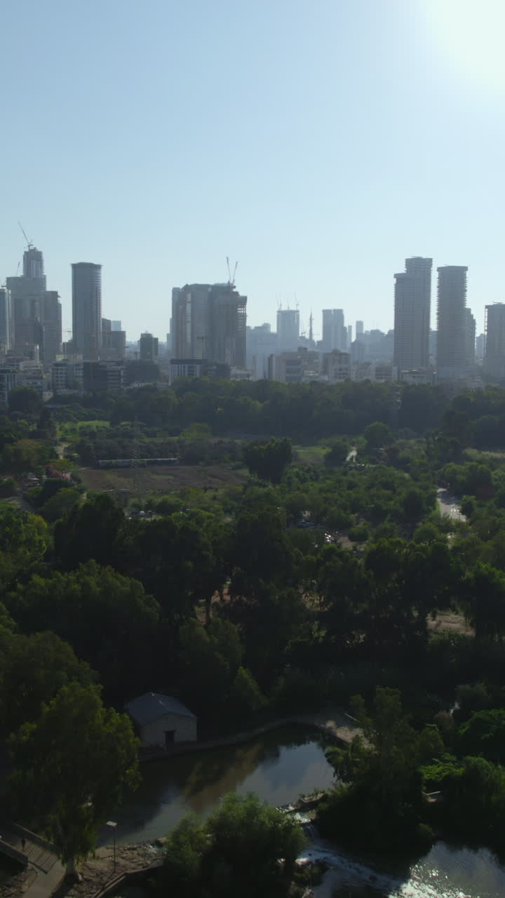 The skyline of Tel Aviv in flight over Yarkon Park - (Ganei Yehoshua) - it's a large park in Tel Aviv, Israel, with about sixteen million visits annually - vertical video