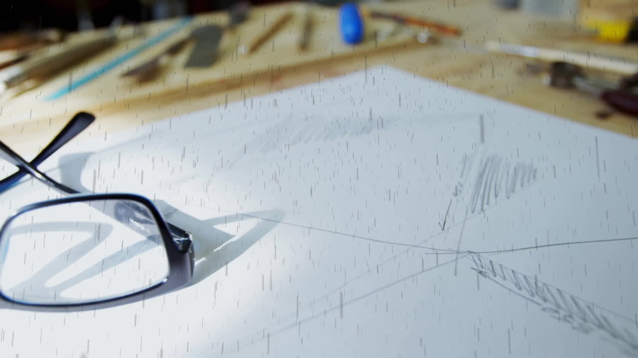 Architectural sketches on desk with drafting tools and glasses in background