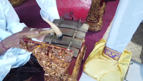 mano cercana y mazo de gamelan angklung músico tradicional, toca música indonesia en la ceremonia religiosa del templo hindú de bali, instrumento de percusión de bronce