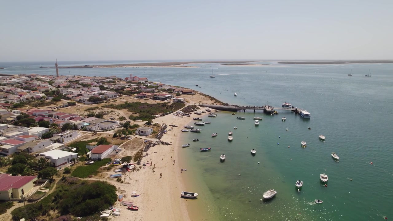Orbita aerea panoramica sopra barche ancorate al largo della spiaggia sabbiosa dell'Isola di Farol a Olhão, Portogallo.
