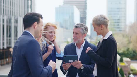business professionals collaborating with a tablet outdoors in a city setting