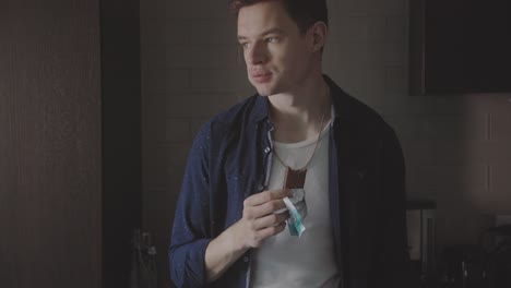 caucasian man standing and eating chocolate while daydreaming