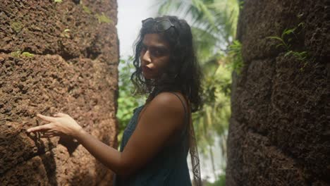 model standing in a passage of an old fortress of laterite walls and posing for camera