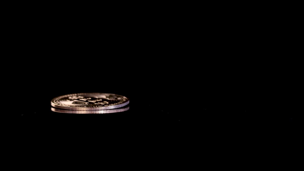 Gold digital coin spins and settles on glossy black background, dramatic lighting, close-up perspective