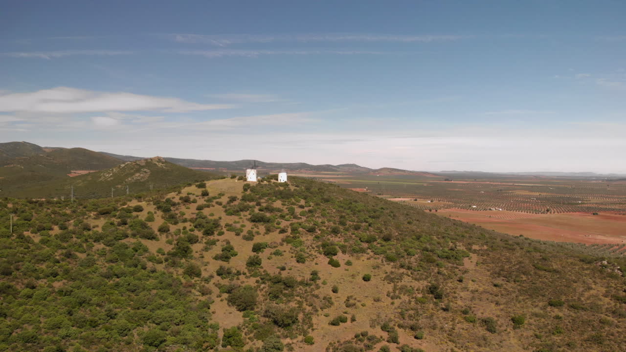 toma aérea de molinos de viento en la colina de la montaña con campos rurales cerca de daimiel en castilla la mancha en un día soleado