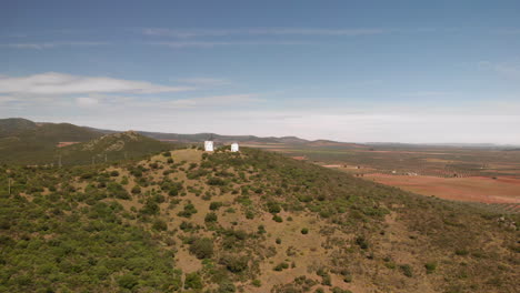 Luftaufnahme-Von-Windmühlen-Auf-Einem-Berghügel-Mit-Ländlichen-Feldern-In-Der-Nähe-Von-Daimiel-In-Kastilien-La-Mancha-An-Einem-Sonnigen-Tag