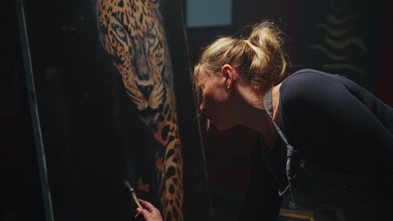 Woman painting a leopard portrait in a studio