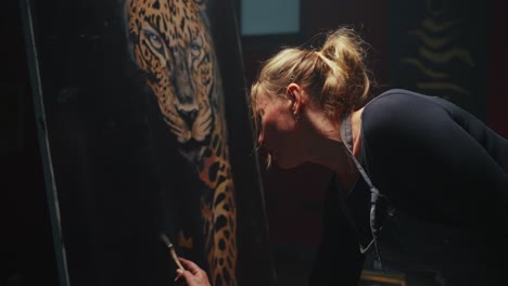 woman painting a leopard portrait in a studio