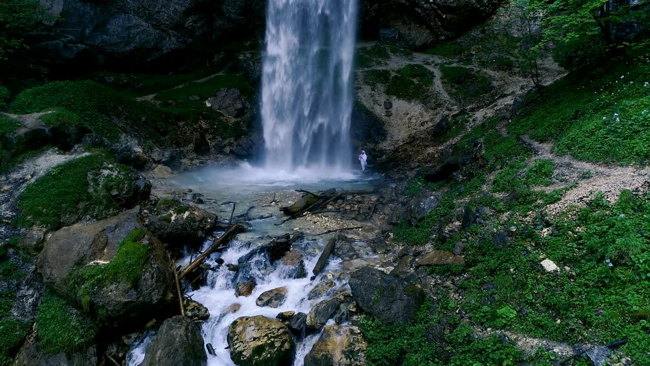 Man with beard is doing waterfall-meditation under big waterfall