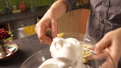 slow zoom-in close up shot of a young woman mixing the egg white foam into the mixture of butter and honey preparing a honey cake filling