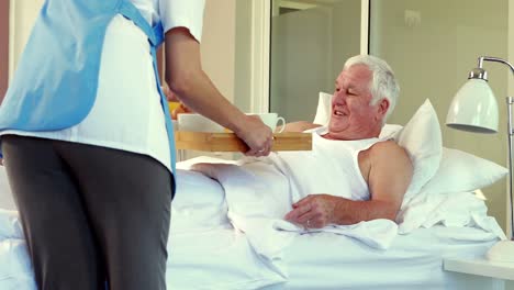 Nurse-giving-tray-with-breakfast-at-senior-man