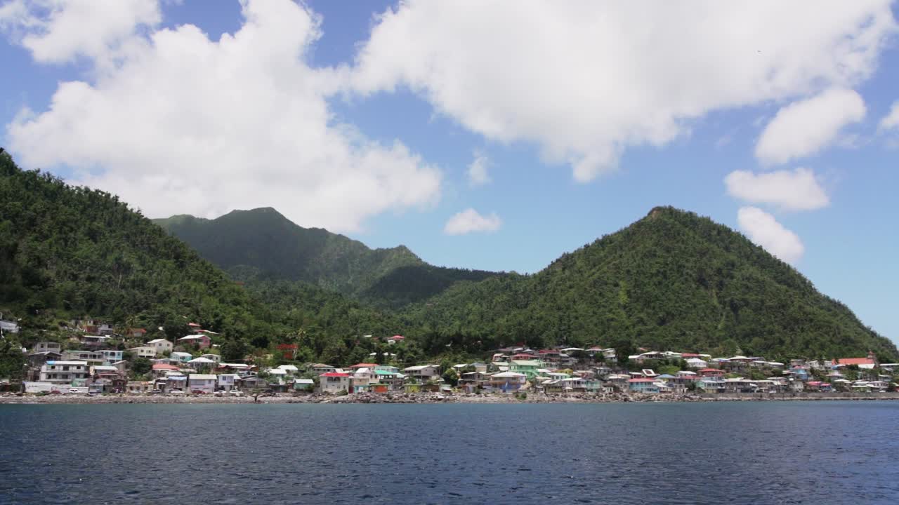 Seaside view of the Dominica, with green hills and houses on a cloudy day