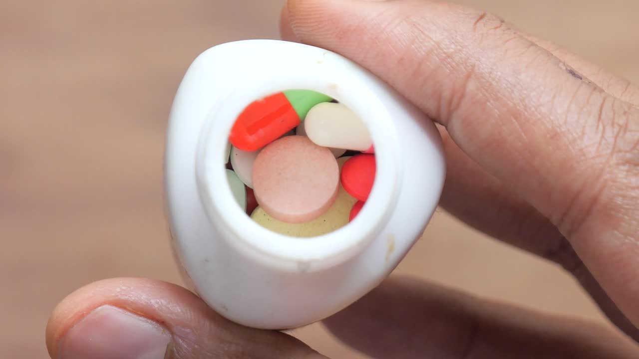 mano sosteniendo un recipiente de pastillas variadas