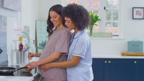 pregnant same sex couple making morning pancakes in kitchen