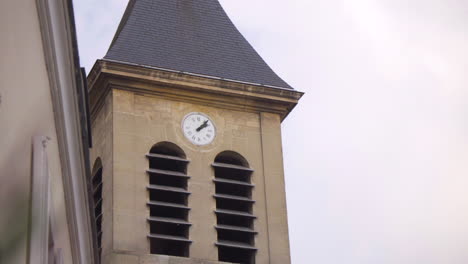 close-up of the clock on the historic sainte geneviève church steeple, asnières-sur-seine. captured during the day, focusing on the intricate clock face and surrounding stonework.