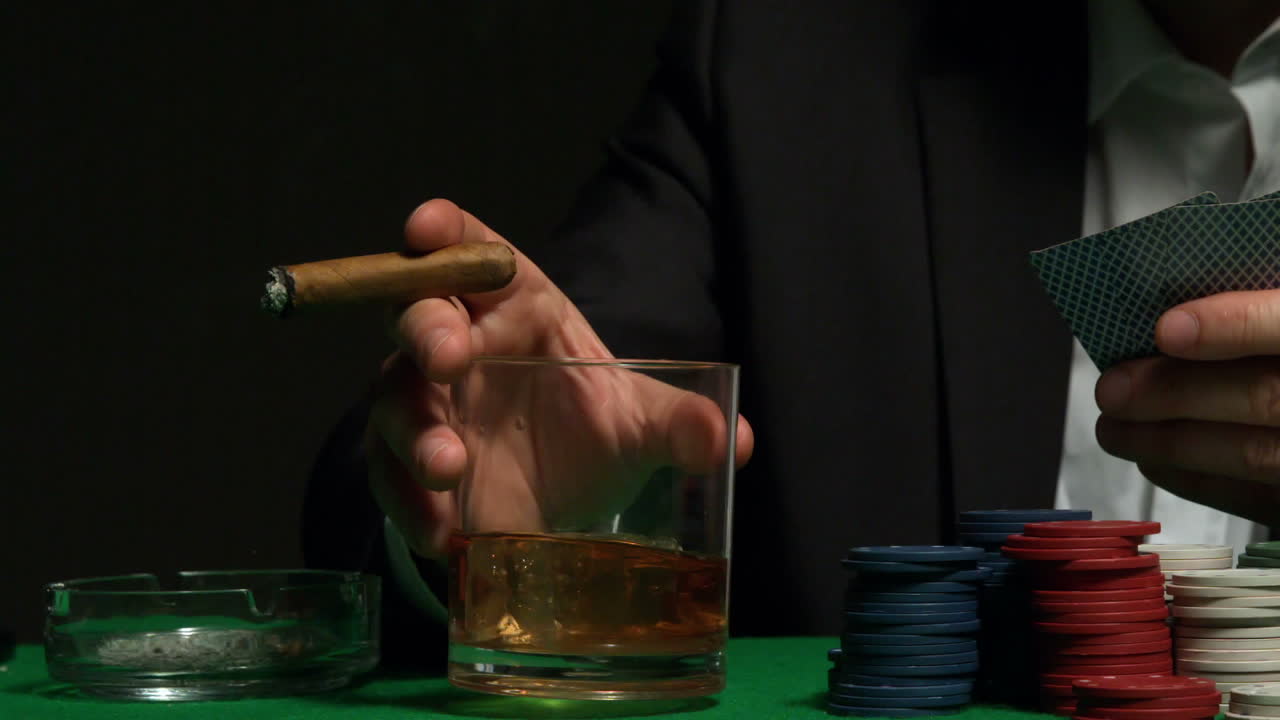Cool gambler picking up his glass of whiskey