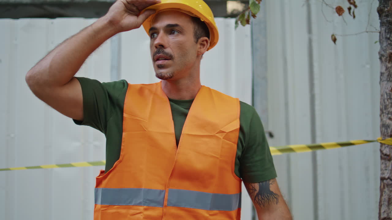Builder guy passing tape at construction site closeup. Man taking off hardhat