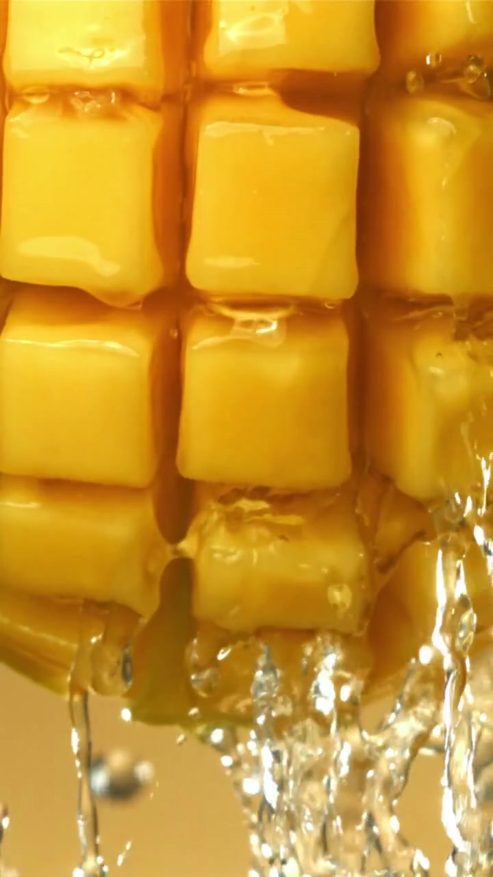 Acqua rinfrescante che schizza e gocciola su cubetti di mango fresco
