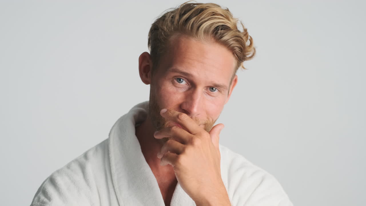 금발의 젊은이가 미소 짓고 포즈를 취하고 있습니다.