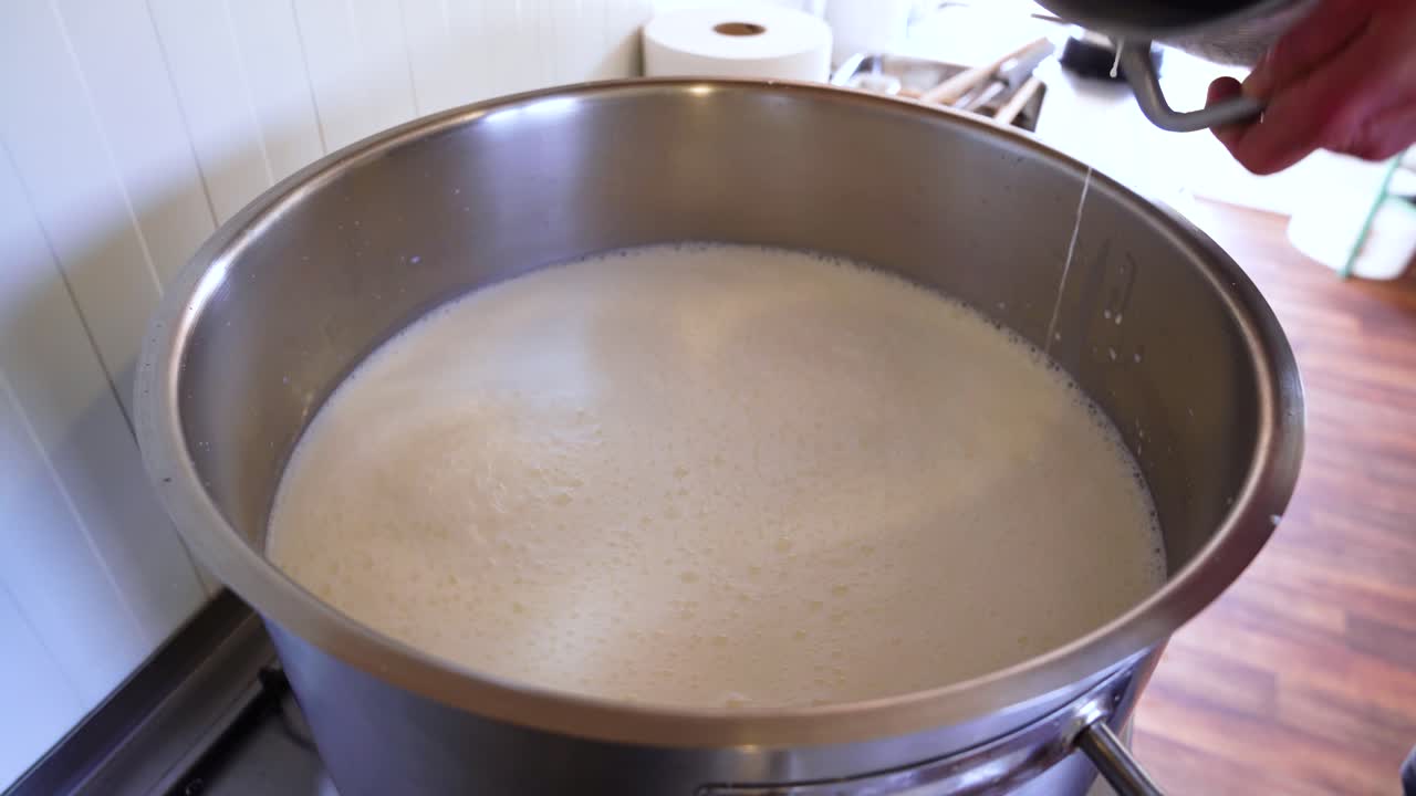 Latte di capra versato da un contenitore d'acciaio in una grande pentola per la pastorizzazione