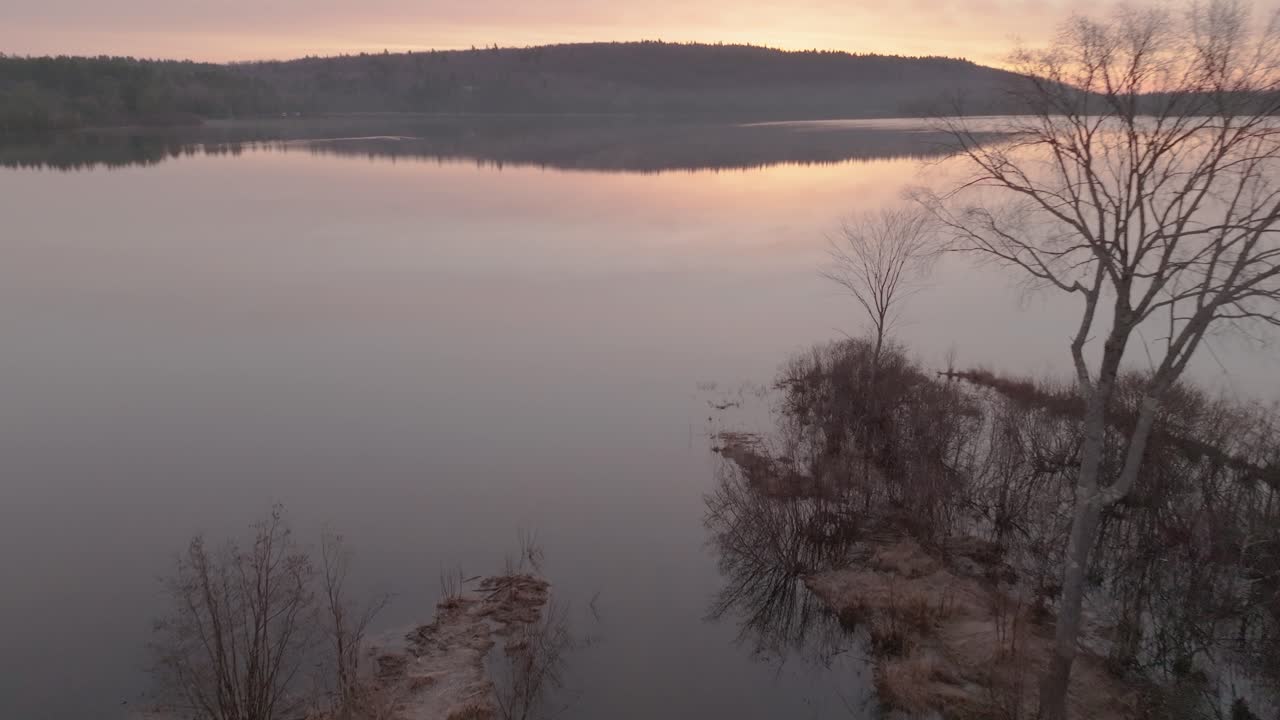 Luftfoto over en bæk, der løber ud i Monson Dam ved solopgang.