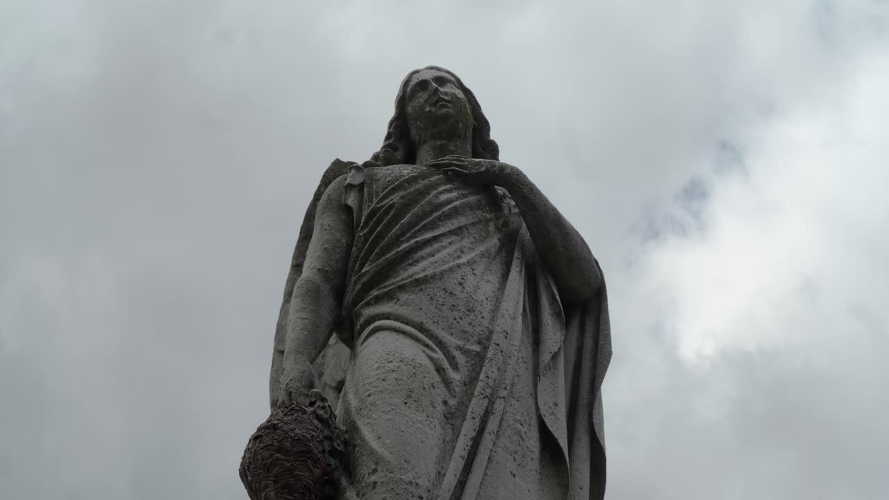 estatua del cementerio con un fondo cronometrado de nubes y cielo