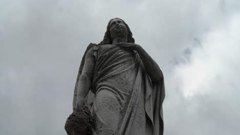 cemetary statue with a timelapsed background of clouds and sky