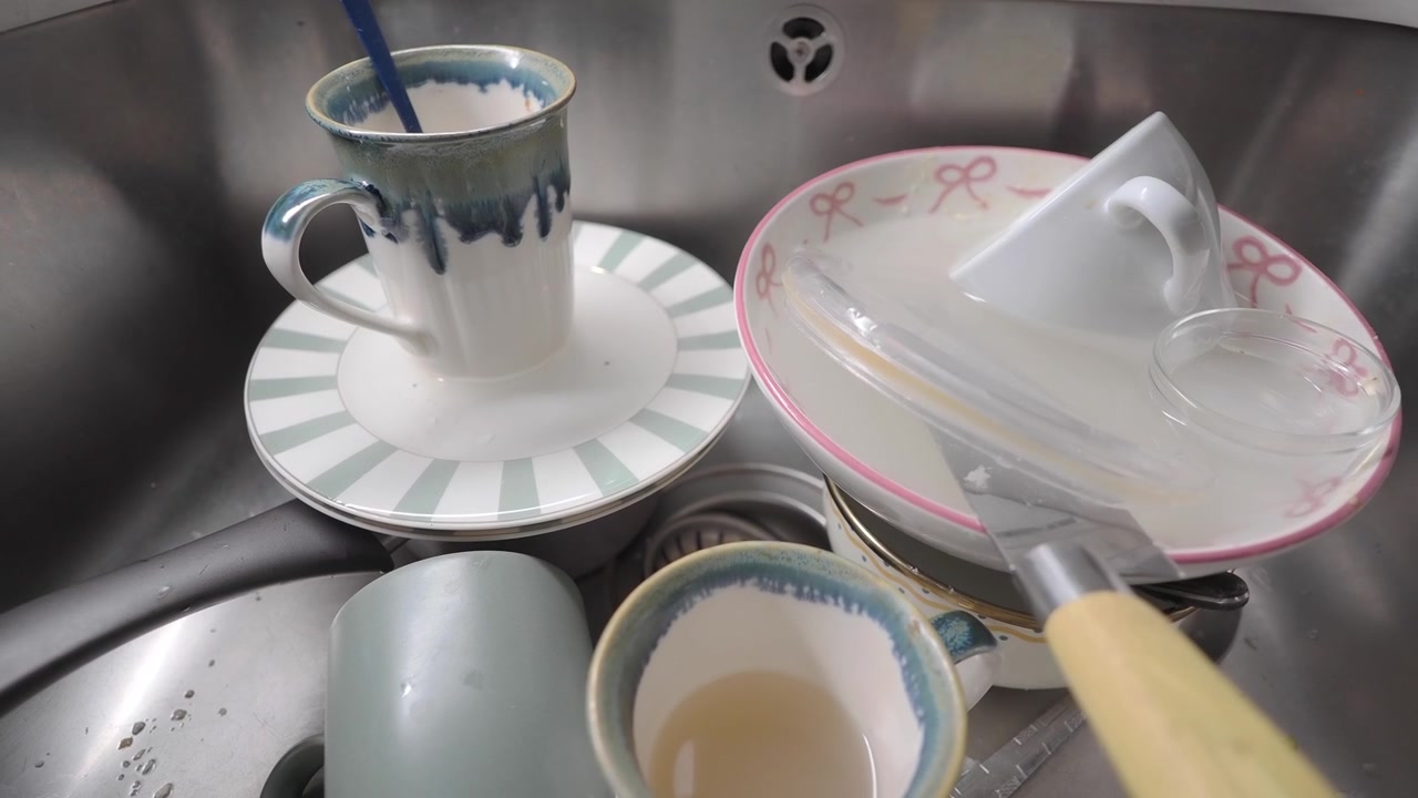 Dirty Dishes Soaking in a Stainless Steel Kitchen Sink