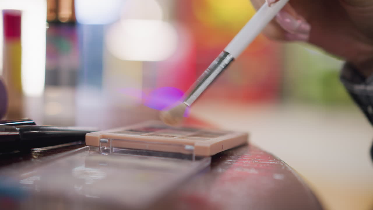 vista parcial de cerca de una chica que usa un pincel de maquillaje para aprovechar el polvo de contorno en la paleta de maquilaje, el proceso de belleza y maquillaje en un fondo borroso. enfoque en el pincel y el polvo