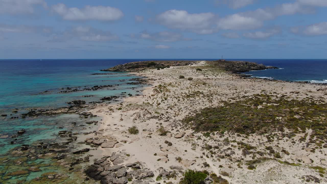 Elafonissi peninsula rocky beaches in Crete Greece with bather couple below, Aerial flyover shot