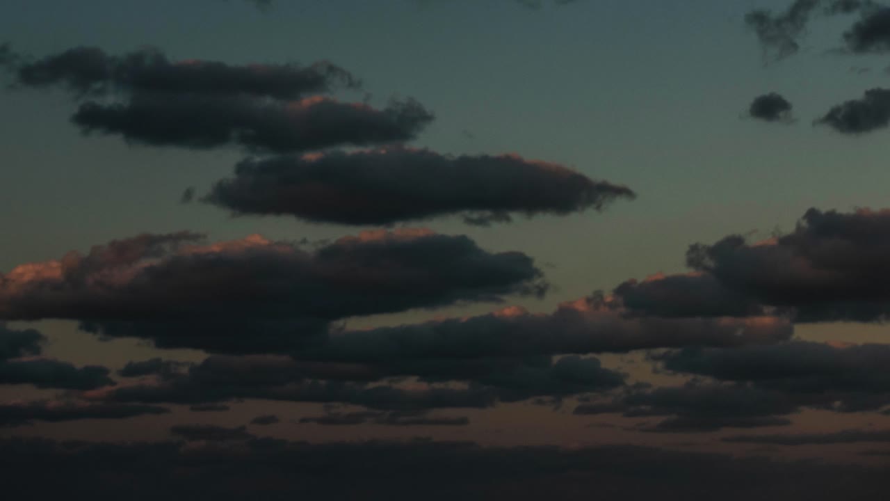 Large clouds moving towards camera at sunset over an ocean and going to darkness
