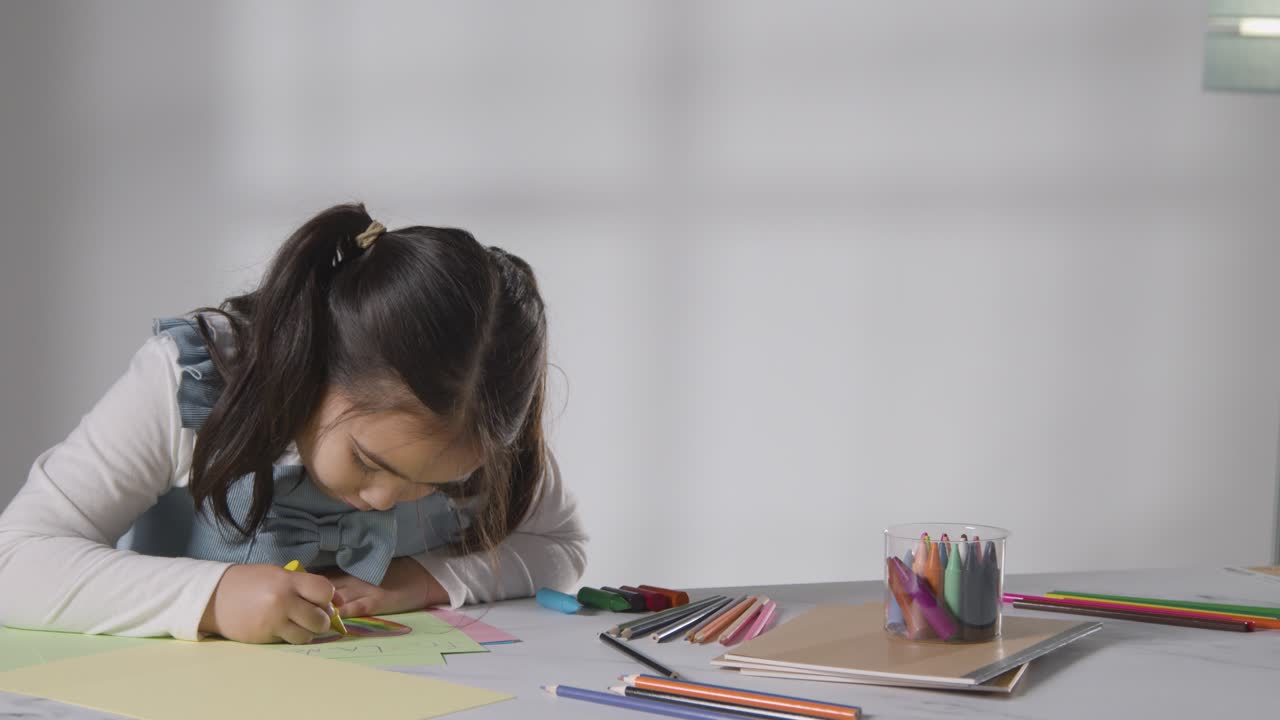 foto de estudio de una niña en la mesa dibujando y coloreando en la imagen 1